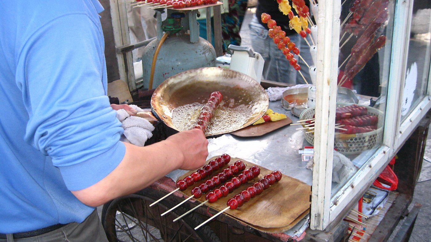 街头摊主在铜锅里蘸糖